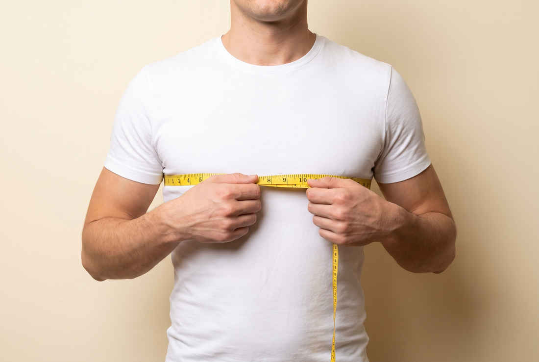Homme mesurant son tour de poitrine avec un mètre ruban par-dessus un tee-shirt