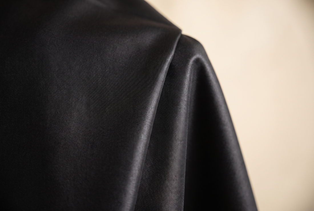 Détail du tissu satiné d'un qamis moderne noir, tombé fluide et surface lisse