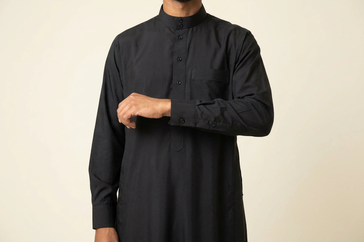 Qamis manche longue noir porté, poignet boutonné et tombé de la manche