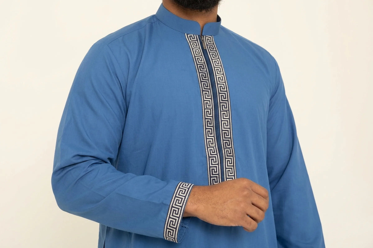 Qamis moderne bleu porté, bande brodée à motif grec sur la poitrine et sur les poignets