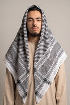 Keffieh classique noir et blanc porté sur la tête, motif filet et chevrons