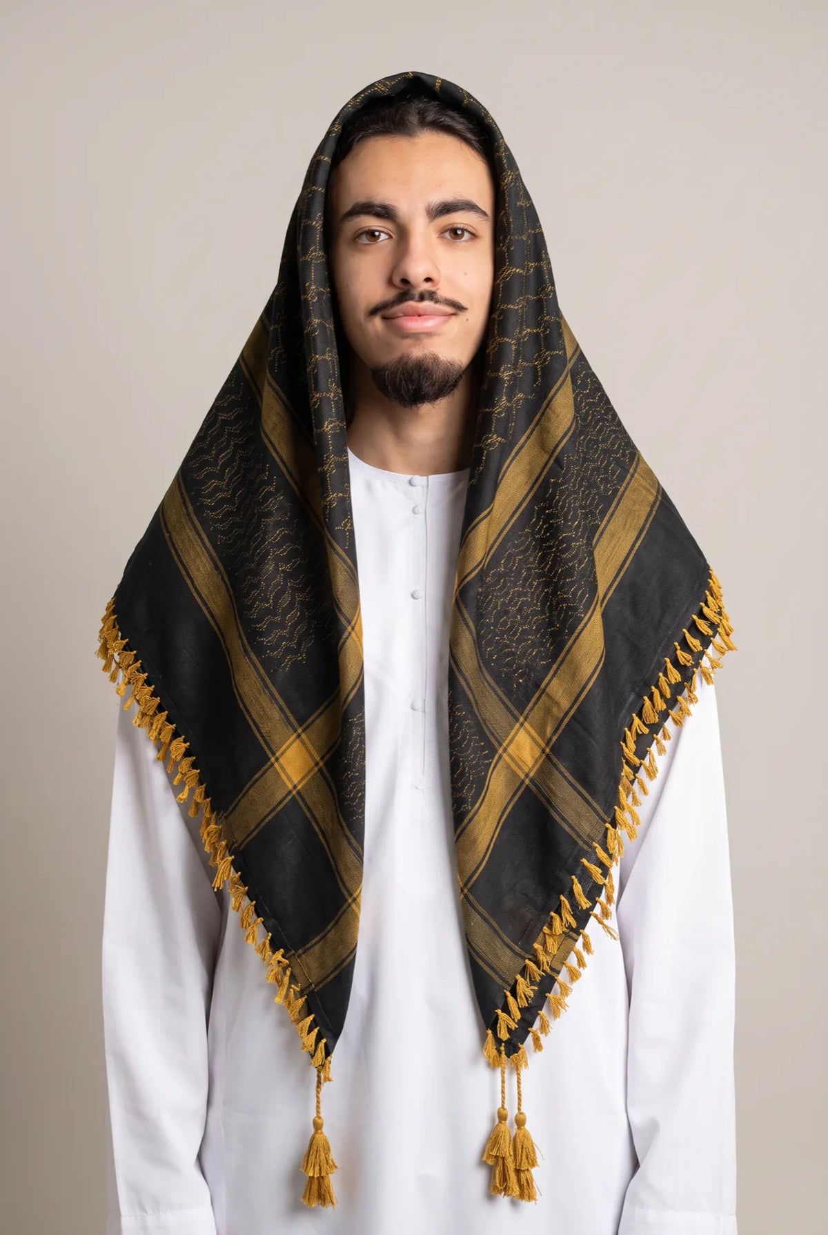 Keffieh luxe noir et or porté sur la tête, franges à pompons