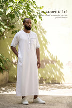 Qamis Issa blanc porté dans une cour ensoleillée, la coupe d'été à manches courtes