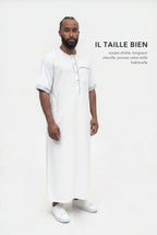 Qamis Issa blanc en pied, coupe droite longueur cheville, il taille bien
