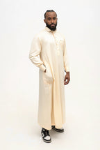 Qamis qatari satiné Adam beige porté, col de chemise et poche poitrine, sur fond blanc