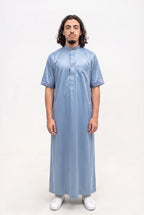 Qamis saoudien satiné Musa bleu porté, col mao et manches courtes, sur fond blanc
