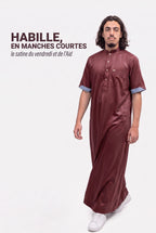 Homme en marche portant le qamis saoudien satiné Musa bordeaux, le satiné en manches courtes