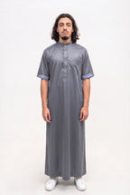 Qamis saoudien satiné Musa gris porté, col mao et manches courtes, sur fond blanc